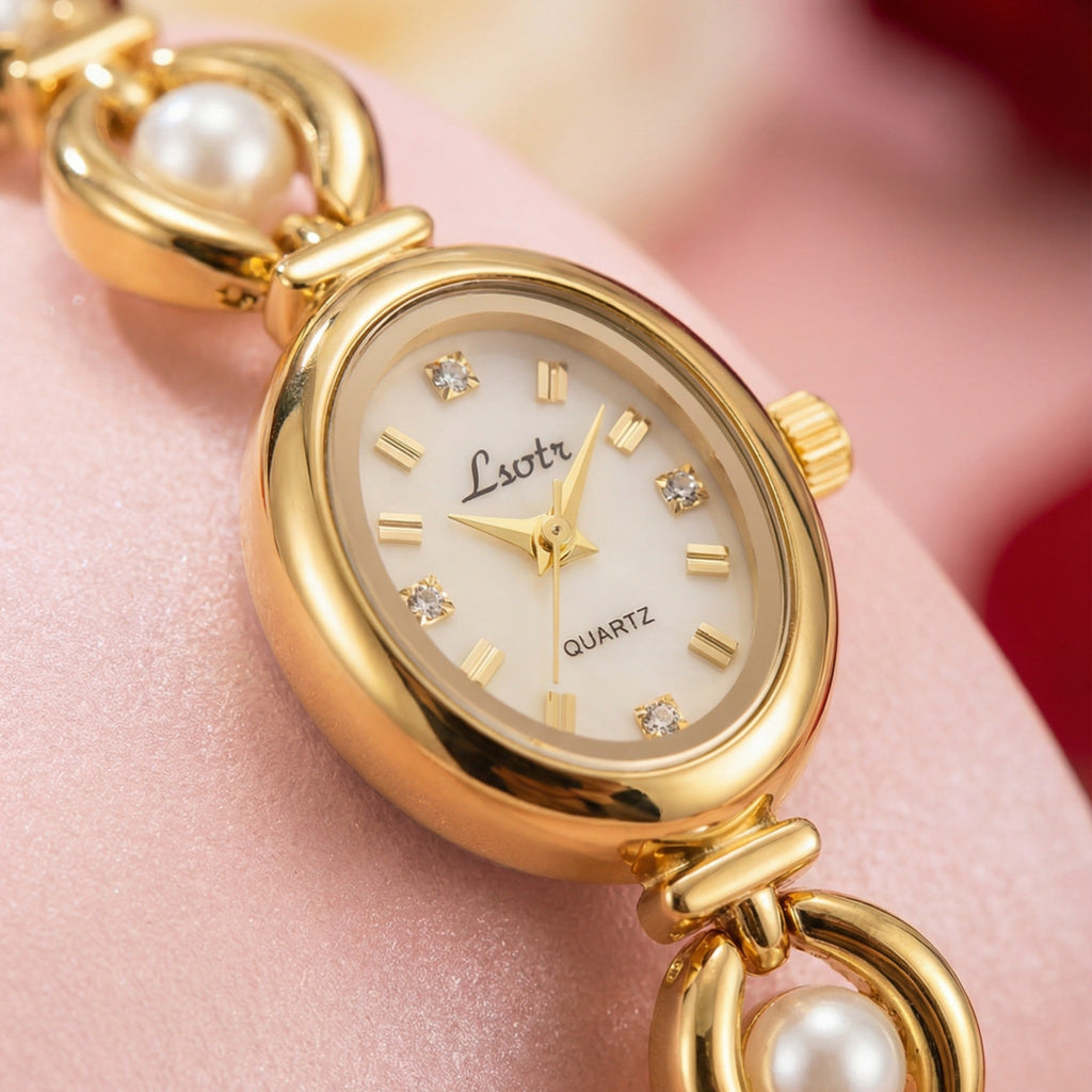 Gold wristwatch with pearl accents on a pink surface
